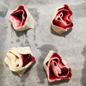 vier Blätterteig-Schnecken ungebacken mit roter Grütze gefüllt