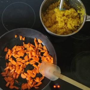 Klein gehackte Karotten und Couscous am Herd